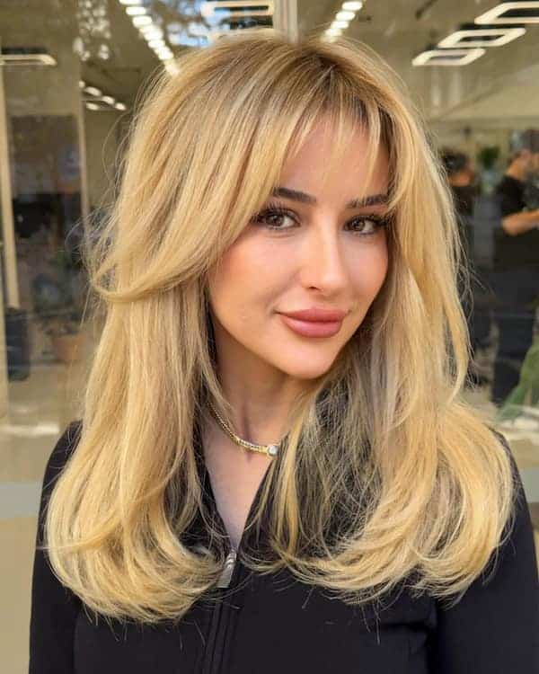 blonde-layered-haircut-with-curved-ends-and-curtain-bangs