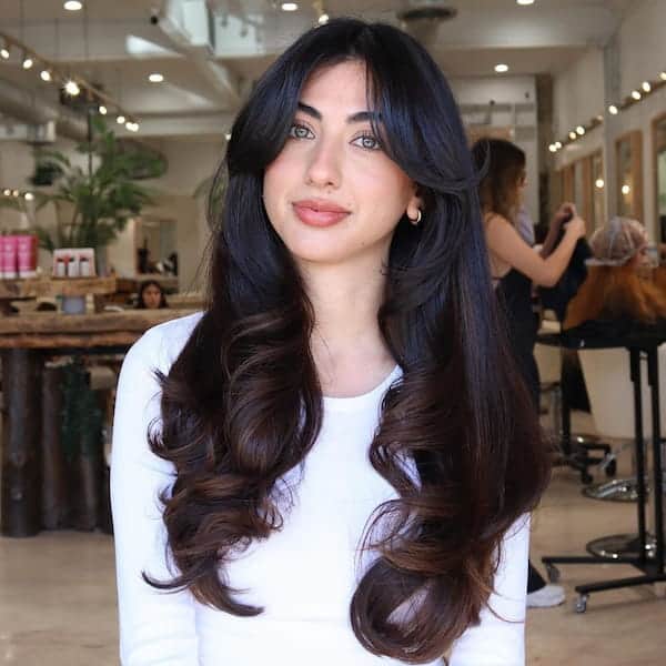 layered-haircut-with-full-blowout-wavy-ends-and-curtain-bangs